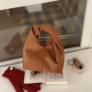 Detail of a brown suede handbag with a unique knotted handle and warm winter styling