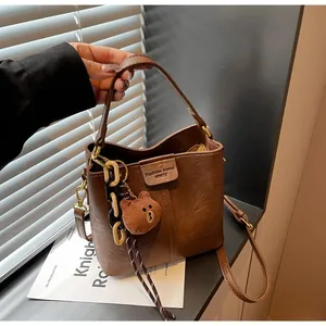 Detail of vintage brown bucket bag with lychee texture and bear charm accessory