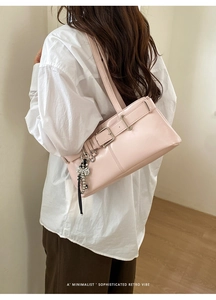 Detail view of pink leather underarm bag with retro buckle and bow charm decoration