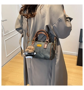 Detailansicht einer Vintage-Zylindertasche mit Plüschbären-Anhänger an einem Modell