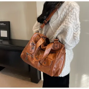 Close-up of brown vintage PU leather handbag with silver zippers on white knit sweater