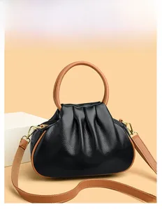 Detail of black lychee grain leather handbag with brown handles and gold hardware