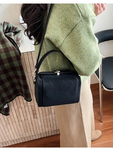 Detailed back view of a minimalist black crossbody bag showing its matte texture and golden lock