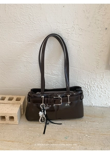 Detail of dark brown glossy leather shoulder bag with silver buckle and chain accessory