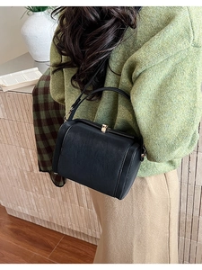 Detail of vintage black doctor bag with gold clasp shown on model with shoulder strap