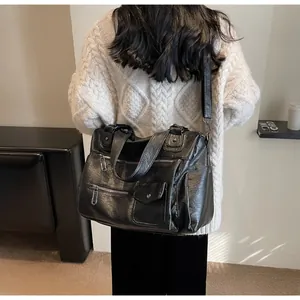 Detail showing high-gloss textured black leather and multiple exterior zipper pockets on the bag