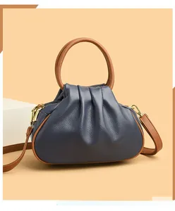 Detailed view of the dark blue pleated cloud bag with brown handles and gold hardware