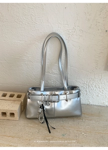 Detail of silver metallic handbag with decorative buckle and metal ball ribbon pendant
