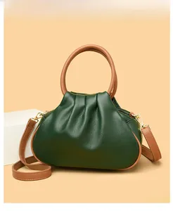 Detail of dark green dumpling bag showing textured lychee leather and tan round handle