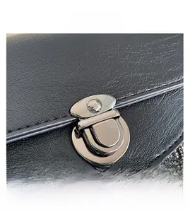 Close-up of a silver metal twist lock on a black pebbled leather tassel crossbody bag