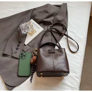 Detail view of vintage dark brown bucket bag showing retro leather texture and bear charm