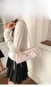 Détail du sac baguette rose à fleurs avec nœud et breloque en forme de cœur argenté
