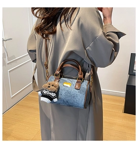 Detail der Denim-Zylindertasche mit Ledergriff und süßem Teddybär-Anhänger-Zubehör