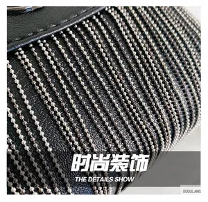 Macro detail of black litchi grain leather bag with decorative silver bead chain tassels