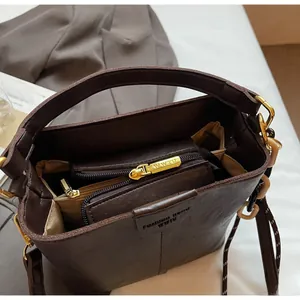 Top view of dark brown bucket bag showing internal zipper compartments and gold hardware