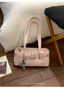 Detail view of pink shoulder bag with elegant beaded pendant and stylish silver buckle