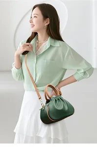 Close-up of dark green lychee grain leather cloud bag with brown handles and gold zipper