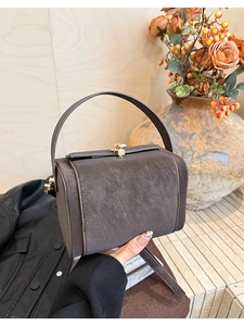 Macro shot of dark brown pebbled faux leather handbag with gold metal clasp detail