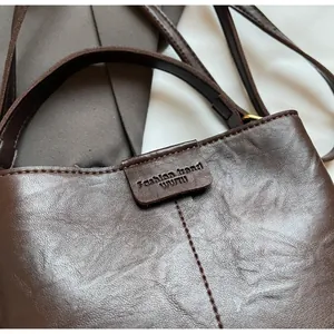 Detail of dark brown vintage bucket bag with matte leather texture and embossed logo