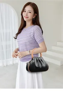 Detail of black pleated dumpling bag with round handle and elegant brown edging