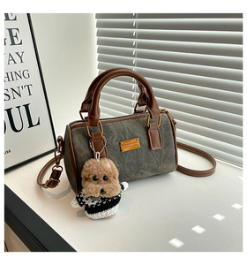 Nahaufnahme der grauen Canvas-Boston-Tasche mit braunen Ledergriffen und Hundeanhänger