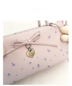 Détail du sac en cuir à motif floral rose avec nœud et pendentif cœur métallique