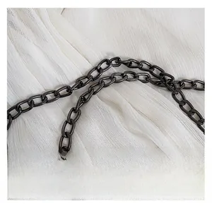 Detailed close-up of dark grey metallic chain strap on soft white chiffon fabric