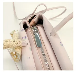 Gros plan de la fermeture éclair argentée sur un sac à main rose à motif floral doux