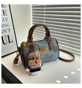 Detail der Denim-Kissentasche mit Ledergriffen und süßem Plüsch-Hundeanhänger