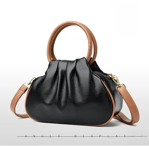 Side view of black lychee grain leather cloud bag with brown round handle and gold hardware