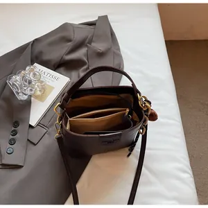 Detail of deep brown bucket bag showing triple-compartment interior and zip pocket