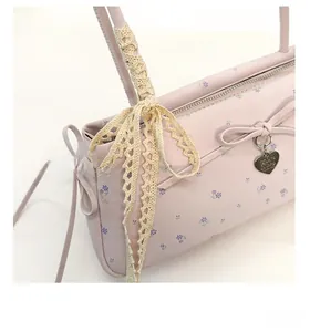 Détail du sac cylindrique rose fleuri avec ruban en dentelle et pendentif cœur