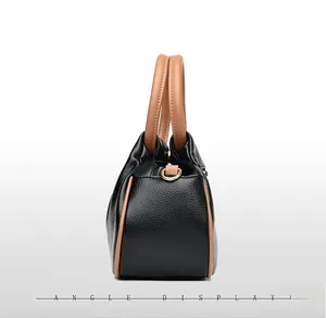 Side view detail of black lychee leather bag with brown handle and gold hardware