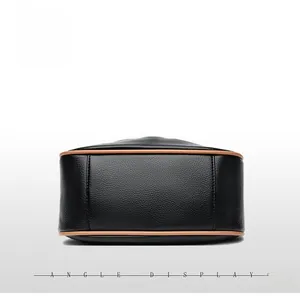 Detailed bottom view of black pebbled leather dumpling bag with brown piping and stitching