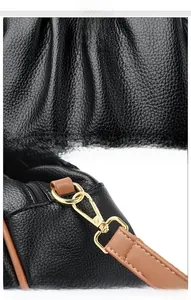 Detail of black lychee grain texture with high-gloss gold metal hooks and brown leather strap