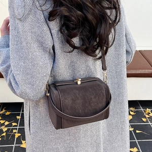 Retro dark brown suede crossbody bag with gold buckle shown on model in autumn street