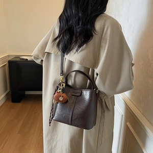 Vintage dark brown leather bucket bag with top handle and teddy bear charm accessory