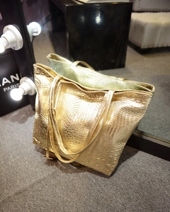 Vue détaillée de la texture crocodile dorée sur un grand sac à main cabas élégant