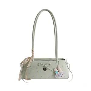 Détail du sac baguette floral vert clair avec ruban dentelle et breloque lapin