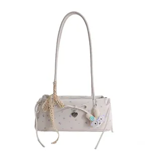 Détail du sac baguette floral avec nœud en dentelle et pendentif lapin en peluche