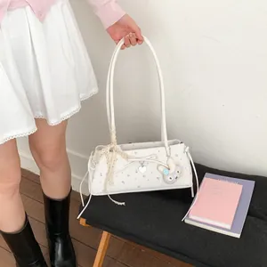 Détail du sac à fleurs avec bordure en dentelle, breloque cœur et peluche lapin mignon