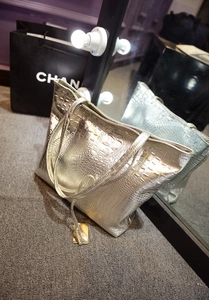 Gros plan sur la texture crocodile argentée du grand sac cabas avec étiquette dorée