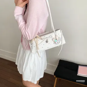 Détail d'un sac d'épaule blanc à fleurs avec nœud en dentelle et breloque lapin en peluche