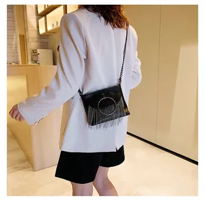 Detail of black PU crossbody bag featuring a large gold ring buckle and long leather tassels