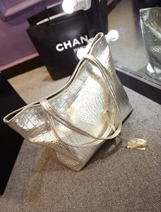 Gros plan d'un sac cabas argenté à motif crocodile avec texture métallique et breloque