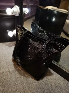 Détail du sac cabas noir à motif crocodile avec une finition en cuir verni brillant