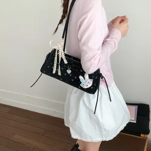 Détail du sac baguette noir avec broderie florale et pendentif lapin mignon