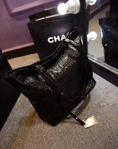 Détail d'un cabas noir en cuir croco brillant avec pendentif métallique doré élégant