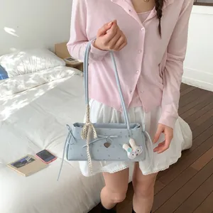 Détail du sac sous le bras bleu clair à fleurs avec nœud et charm de lapin en peluche