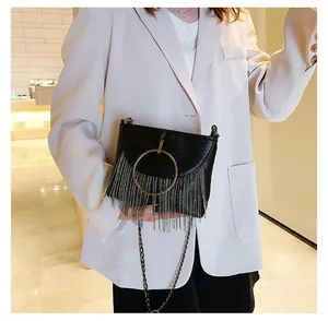 Detail of black PU crossbody bag with golden ring and silver chain tassel fringe